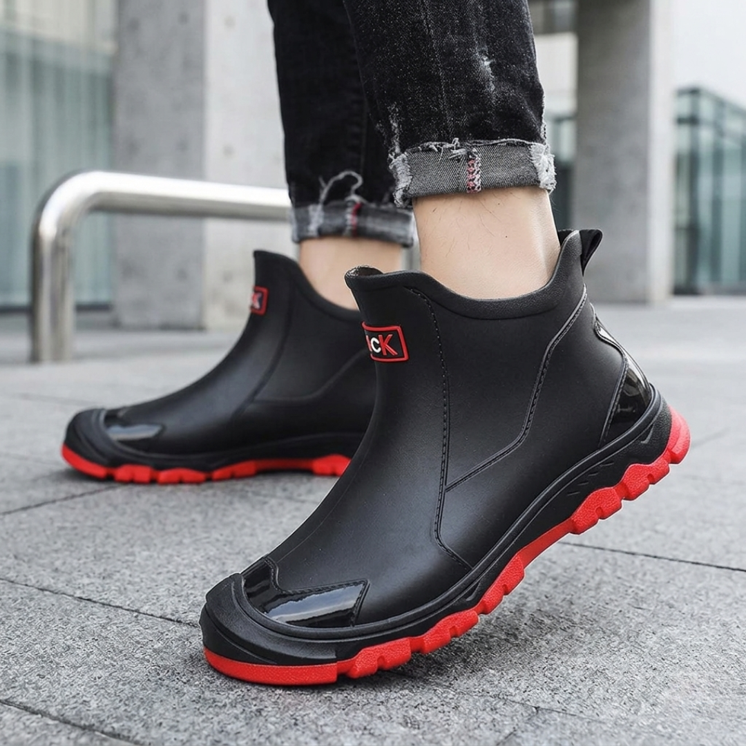Close-up of black slip-on boots with red lug soles and side logo patch