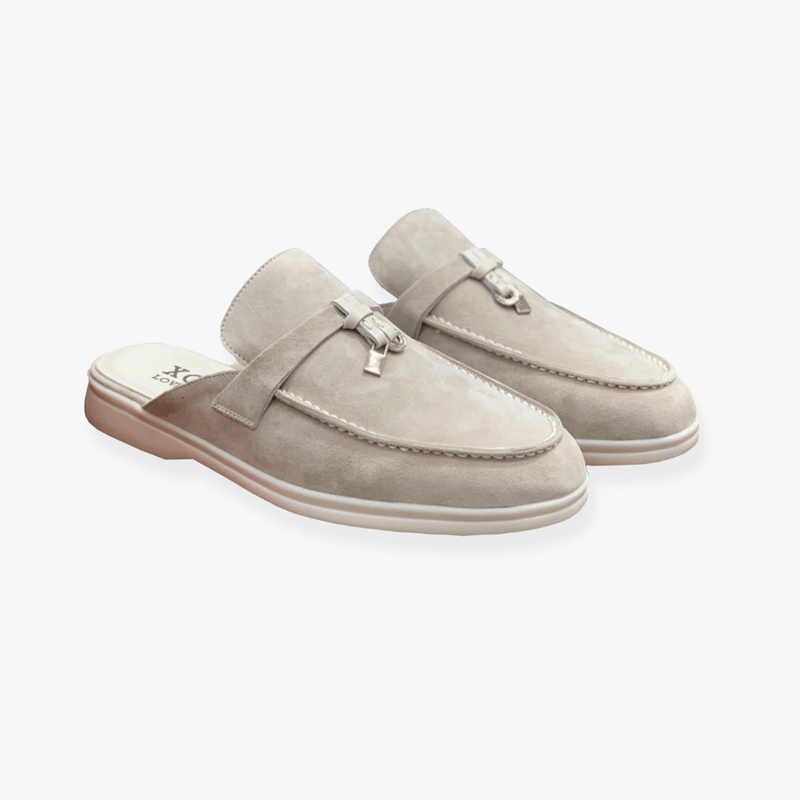 Beige slip-on suede mules with silver metal accent and minimalist open-back design