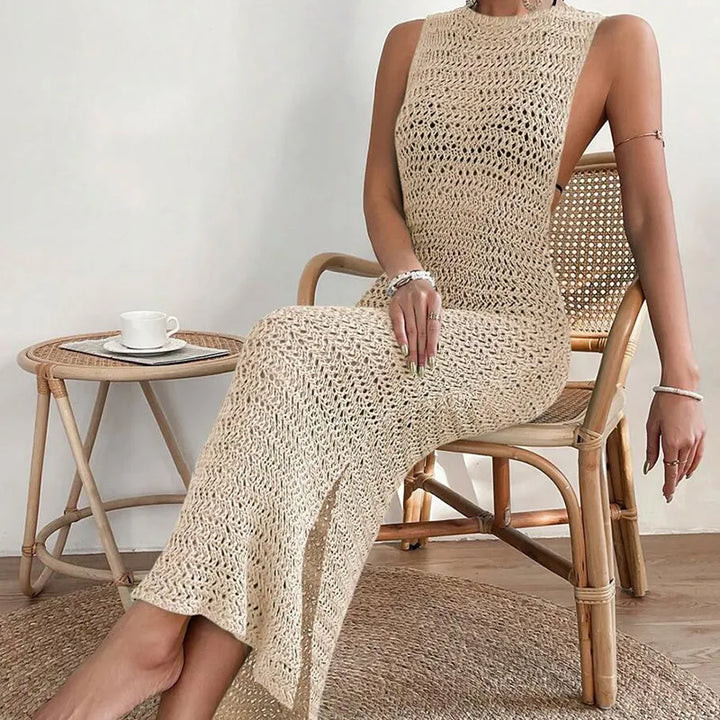 Seated model wearing beige open-knit crochet maxi dress highlighting fabric drape