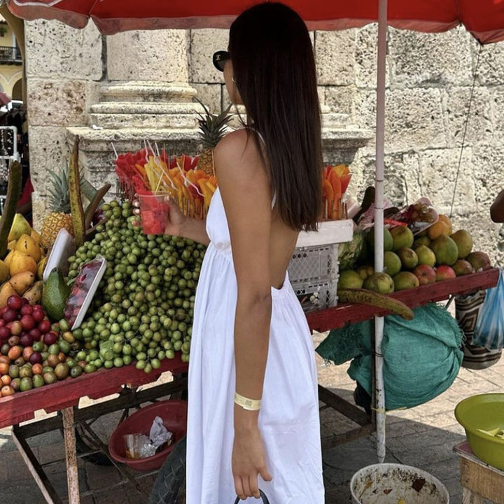 White open back maxi dress worn at outdoor fruit market for vacation
