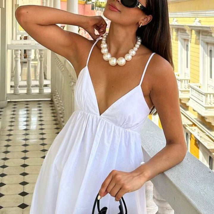 White V-neck maxi dress modeled on balcony with pearl necklace and sunglasses