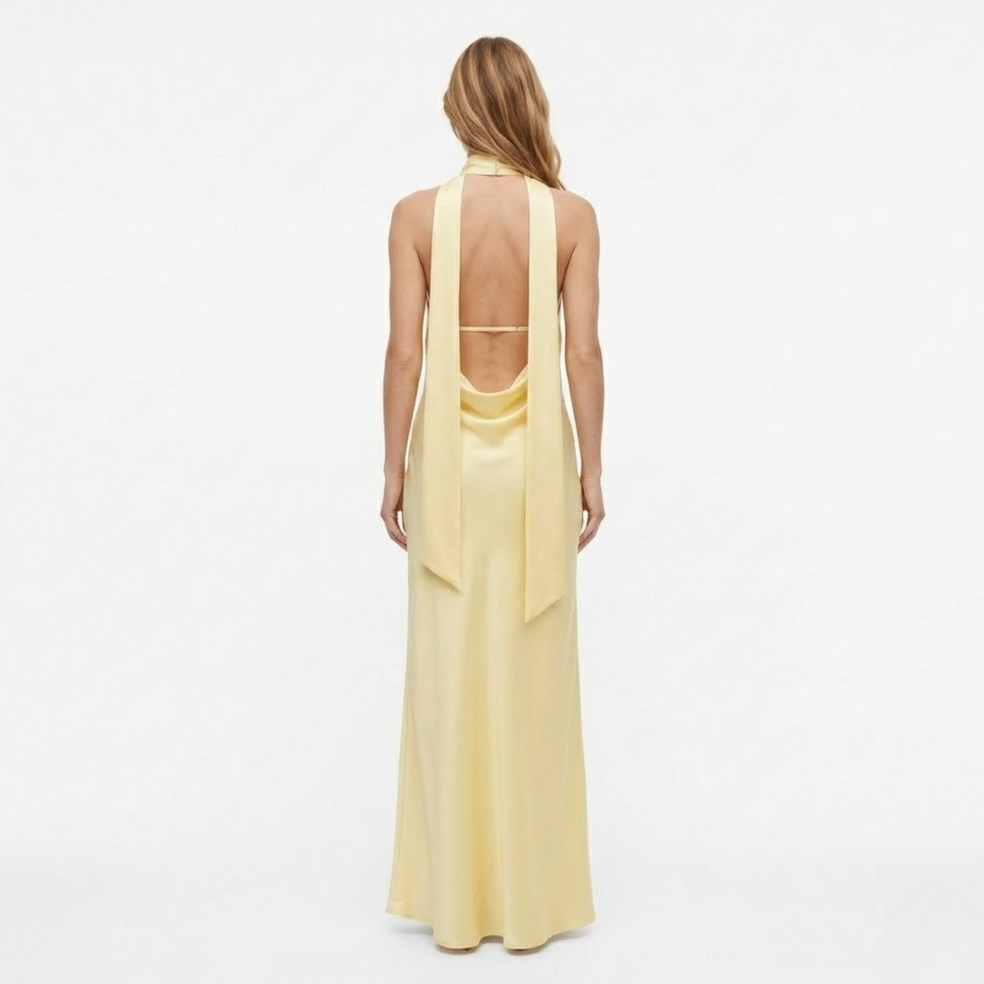 Back view of woman wearing yellow halter neck maxi dress with exposed upper back
