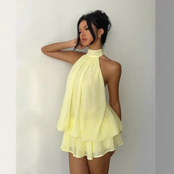 Pale yellow halter neck mini dress with open back and tiered ruffled chiffon hem