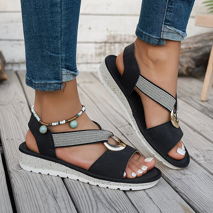 Black women's summer sandals with thick white speckled sole worn on wooden deck
