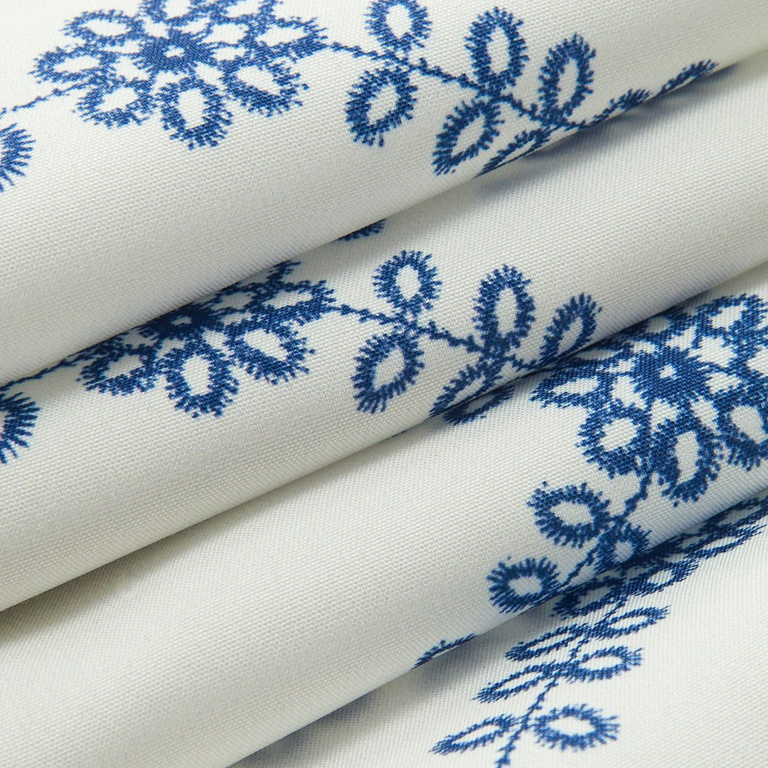 Close-up of textured white cotton blend fabric with raised blue embroidery