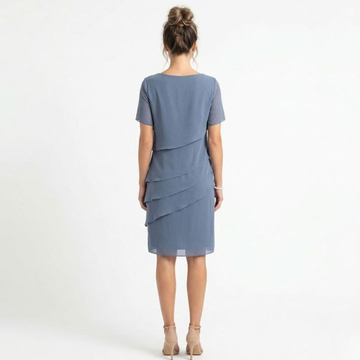 Back view of blue tiered chiffon dress featuring asymmetrical ruffled side drape