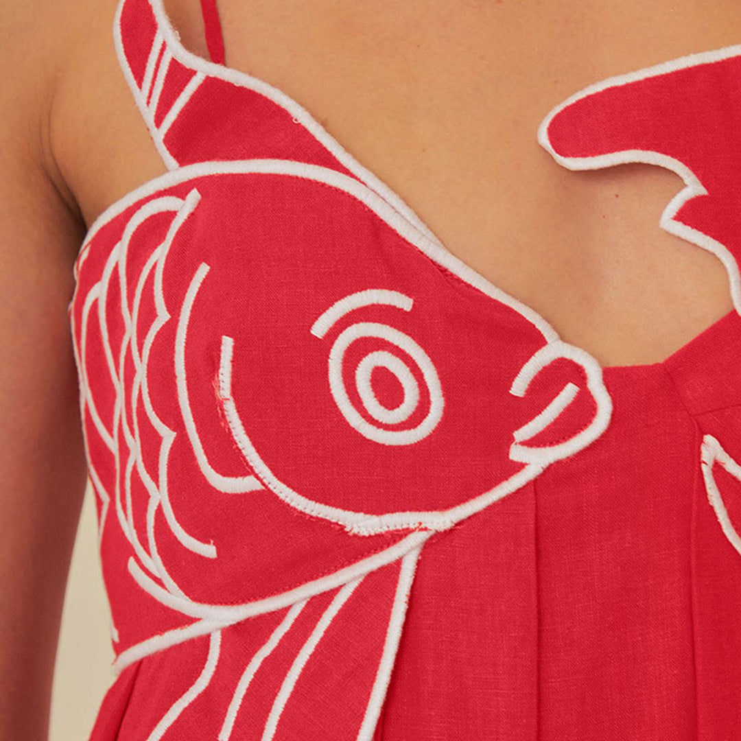 Close-up of red dress bodice showing raised white embroidered fish scale texture